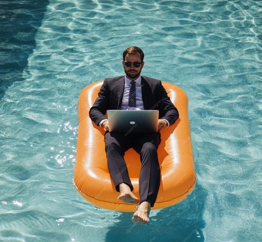 expert comptable en costard allongé dans une piscine et travaillant sur son ordinateur.